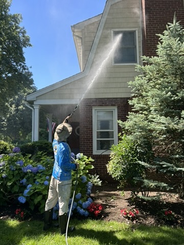 Clean N’ Go technician soft washing a Jericho home’s siding