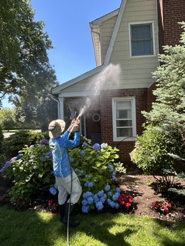 House washing — Clean N' Go technician soft washing a Long Island home